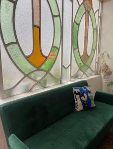 a green couch in front of three stained glass windows at Rivière Hostel in Cordoba
