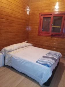 Cama en habitación con pared de madera en casa vacacional, en Ledaña