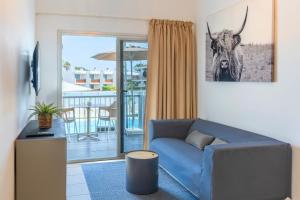 un salon avec un canapé bleu et une photo de taureau dans l'établissement Tajinaste Beach Gay Men Only, à Playa del Ingles