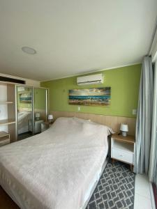 a bedroom with a white bed and a green wall at Flat Manaíra Palace in João Pessoa