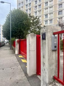 une clôture rouge sur un trottoir à côté d'un bâtiment dans l'établissement Chambre privée dans un appartement partagé, à Villeurbanne