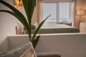 1 dormitorio con cama y planta en The Sunny Flair, Relaxing Experience, en Morro del Jable