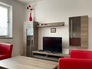 a living room with a flat screen tv and red chairs at Natur pur im Erzgebirge in Breitenbrunn