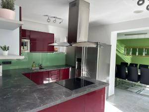 una cocina con armarios rojos y encimeras negras en Outlet Center House, Pool-Jacuzzi-Garden-Sundeck, en Parndorf
