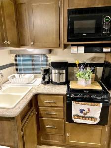 a kitchen with a stove and a sink and a microwave at 63 Acre Farmstay - A luxury farm experience in San Mateo