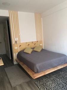 a bed with a wooden frame in a bedroom at Bello Monoambiente en El Prado in Cochabamba