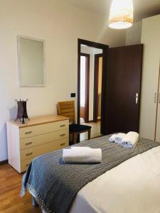 的住宿－Alloggio ai piedi del Cansiglio，一间卧室配有床和一个带毛巾的梳妆台。