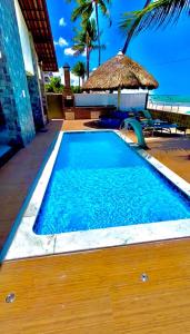 a swimming pool with a straw umbrella and blue water at Pousada La Riviera in Maragogi