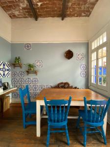 a dining room with a wooden table and blue chairs at Hostel Home in Mexico City
