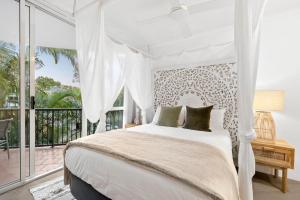 a white bedroom with a bed and a balcony at Penthouse with Private Roof top terrace- NOOSA in Noosa Heads