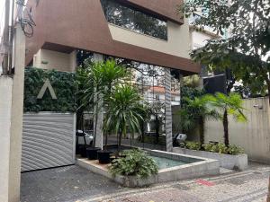 a building with a swimming pool and palm trees at Locking's Lourdes 13 in Belo Horizonte