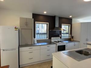 a kitchen with white cabinets and a white refrigerator at Foreshore Mukies 2,0 in Ahipara