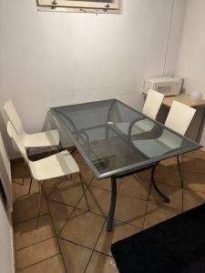 a glass table and two white chairs in a room at Room A in Malmö