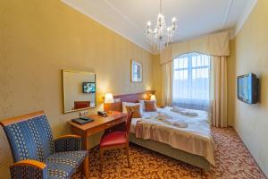 een hotelkamer met een bed, een bureau en een stoel bij Spa Resort PAWLIK-AQUAFORUM in Františkovy Lázně