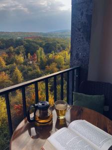 una mesa con una taza de té y libros en el balcón en Цахкадзор кечи аус Уютное студио с видом на лес - Cozy studio with stunning forest views, en Tsaghkadzor