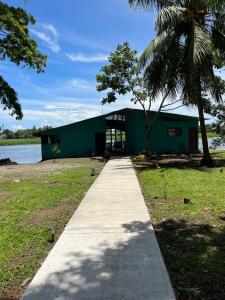 a green building with a sidewalk in front of it at The Secret Eco Lodge in Tortuguero