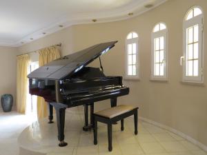um piano preto numa sala com uma cadeira em Villa Moments - Guest House em Portimão
