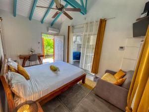 a bedroom with a bed and a couch and a window at Gites Fleurs d'abeilles in Anse-Bertrand