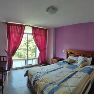 een slaapkamer met een bed met paarse muren en een raam bij HOTEL LAS TANGARAS DE MINDO in Mindo