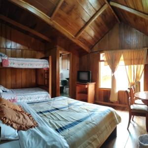 a bedroom with two beds and a tv in it at HOTEL LAS TANGARAS DE MINDO in Mindo