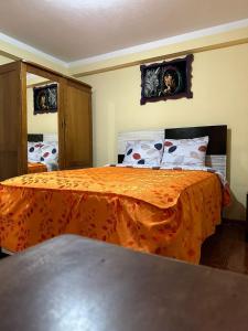 1 dormitorio con 1 cama con colcha de color naranja en Hospedaje Qorichaska's en Cusco