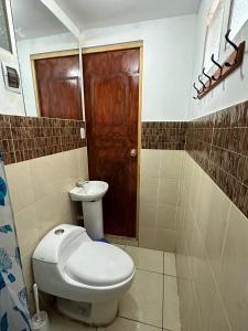 a bathroom with a toilet and a wooden door at Hospedaje Qorichaska's in Cusco