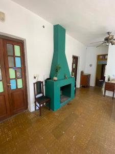 a living room with a green fireplace and a chair at Hospedaje centro erks in Capilla del Monte