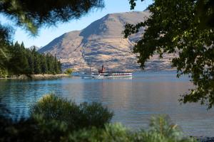 a boat on the water in front of a mountain at Q1 Luxury Central Apartment in Queenstown