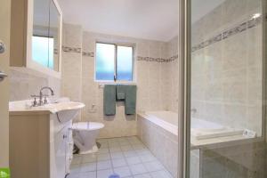 a bathroom with a tub and a toilet and a sink at Bel Mondo Apartments in Wollongong