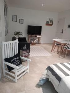 a living room with two white chairs and a television at Paisaje 1 in Comodoro Rivadavia