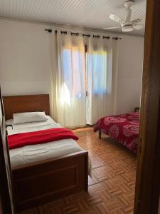 a bedroom with a bed with a red blanket and a window at Pousada Ananda in Osório