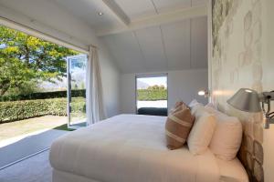 a bedroom with a white bed with a large window at Arrow Wood - Minutes to Arrowtown, Golf and Wineries - Luxury Living in Arrowtown +28 photos