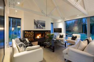 a living room with white furniture and a fireplace at Arrow Wood - Minutes to Arrowtown, Golf and Wineries - Luxury Living in Arrowtown
