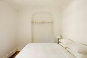 a white bedroom with a bed and a lamp at Miss Midgley's - Refectory in Brisbane