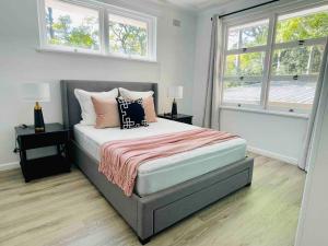 una camera da letto con un letto grande con due finestre di Renovated charming & cozy house (Walk to Station) a Sydney
