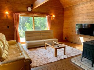 uma sala de estar com um sofá e uma mesa em 白馬のスキー場まで４分お洒落なログハウス『白馬 MAMMOTH HOUSE』 em Hakuba