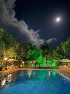 una piscina por la noche con luna llena en Guaratiba, paraíso particular Apto 23, en Prado
