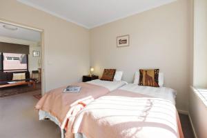 メルボルンにあるNorthcote Charm Spacious and Quiet Suburban Stayのベッドルーム1室(ベッド2台付)、リビングルームが備わります。