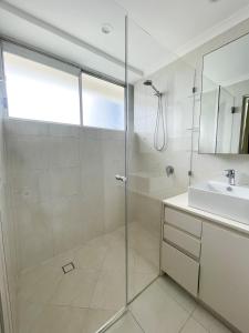 a bathroom with a glass shower and a sink at Baronnet Apartments in Gold Coast
