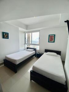 a bedroom with two beds and a large window at Apartamentos Cartagena Oceano - Eliptic in Cartagena de Indias