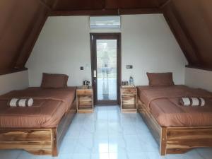 two beds in a room with a room with a window at D' Carasti Bungalow in Masbagik