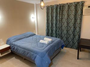 um quarto com uma cama azul com toalhas em Hotel Yatay em Puerto Iguazú
