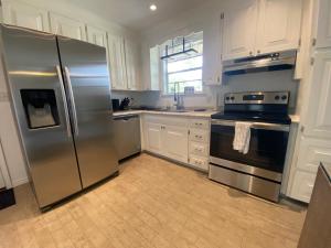 uma cozinha com electrodomésticos de aço inoxidável e armários brancos em Spacious Ranch Home Near Airport em Pensacola