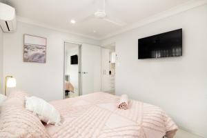 a white bedroom with a bed and a flat screen tv at Air-Con, Netflix, Close to Transport & Private in Brisbane