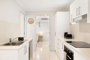 a white kitchen with a sink and a counter at Air-Con, Netflix, Close to Transport & Private in Brisbane
