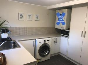uma cozinha com uma máquina de lavar roupa e um lavatório em Jacaranda House Garden Suite em Brisbane