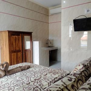 a bedroom with a bed and a tv on a wall at Santhi Graha by NauliTabitha in Legian