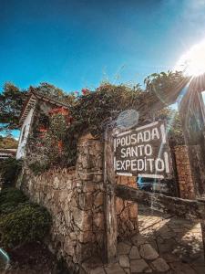 a sign for a resort on a stone wall at Pousada Santo Expedito in Tiradentes