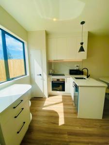 a kitchen with white cabinets and a large window at Holiday / Short term Rent in Auckland