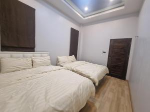 a white room with two beds in it at DPool Villa in Sattahip